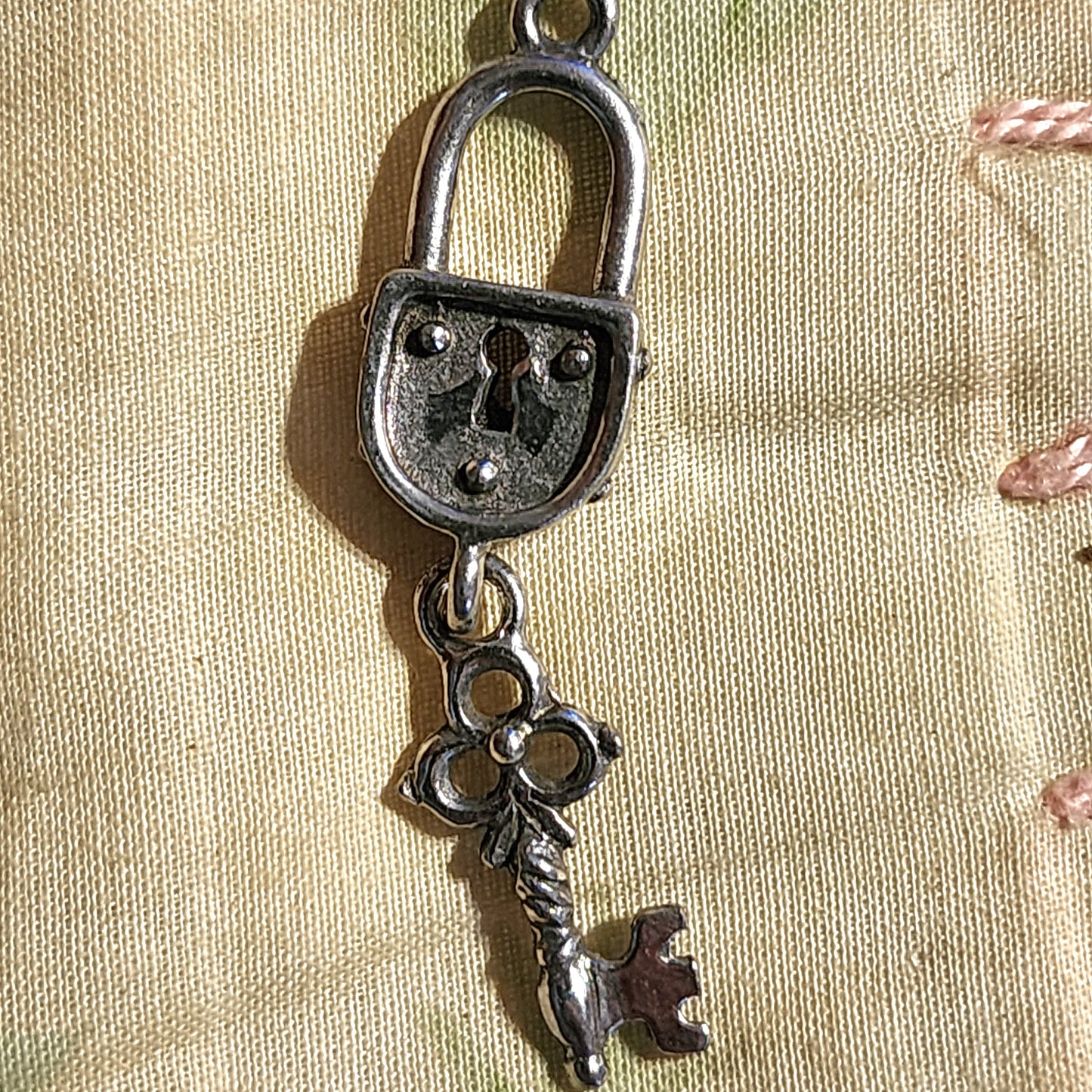 Metal padlock and dangling key charm